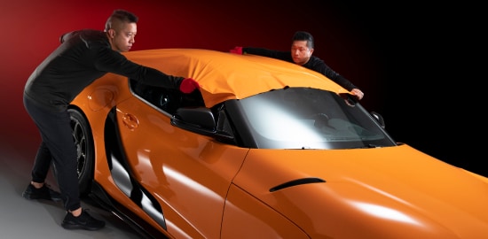 Auto technicians installing paint protection on the roof of a sports car.

