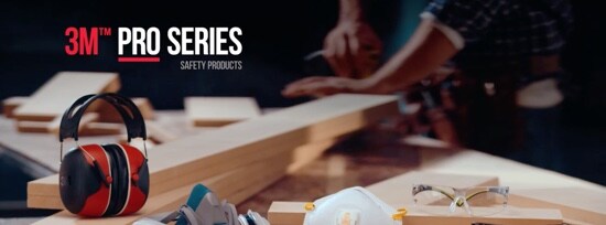 Ear muffs, a reusable respirator, a disposable respirator, and safety glasses displayed on a workbench.
