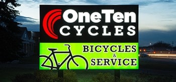 Enseigne de OneTen Cycles à l’extérieur d’un édifice la nuit.
