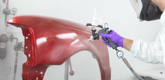 Un peintre utilisant un Pistolet de pulvérisation à haute performance 3M(MC) sur une aile rouge.
