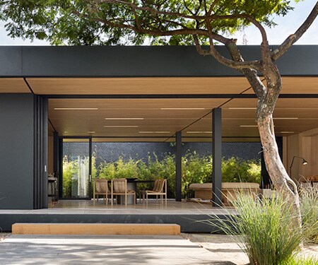 Exterior of modern home with matte black and light wood finishes.
