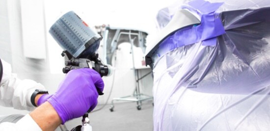 Des mains gantées utilisant le Pistolet de pulvérisation à haute performance 3M(MC) sur une voiture masquée.
