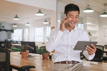 Une personne souriante, en pleine conversation, parcourant des ressources sur sa tablette.

