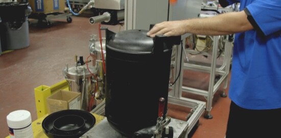 A video still of a man in a manufacturing facility.
