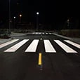Low-angle shot of white painted crosswalk across road.