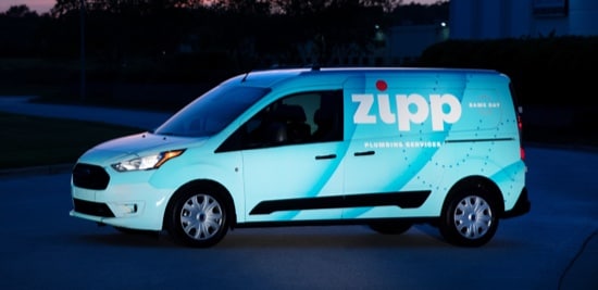 A fleet van wrapped in a white and blue reflective film.
