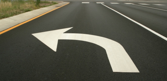 Large left-turn arrow on pavement in road’s turn lane.
