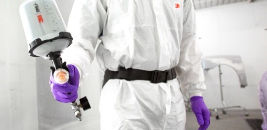 Un travailleur d’atelier de carrosserie en combinaison tenant le Pistolet de pulvérisation à haute performance 3M(MC) avec un Godet de pulvérisation PPSMC 3MMC de Série 2.0.
