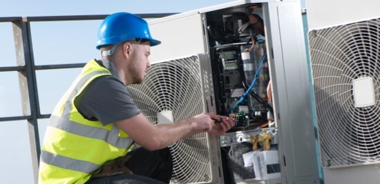 Un électricien travaillant sur un système de climatisation.
