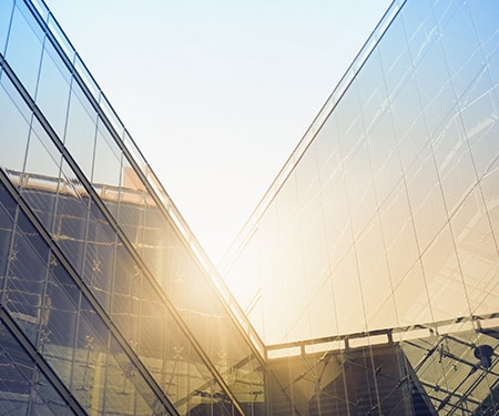 Rayons de soleil embrasant des bâtiments anguleux aux façades vitrées.
