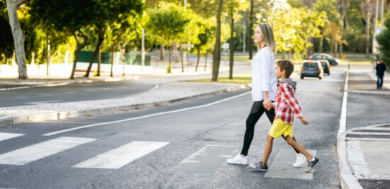 Woman and child confidently crossing the street at mid-block crossing with curb bump out and painted lines.
