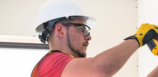 Un homme portant un casque de protection avec un dispositif de protection de l&rsquo;ouïe et des lunettes de protection.