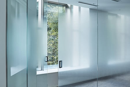 Murs et portes en verre d’une salle de conférence rehaussés d’un effet dégradé givré grâce aux finitions pour verre FASARA.
