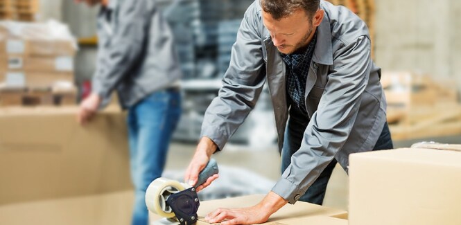 Ouvriers scellant des cartons d’expédition dans un entrepôt.
