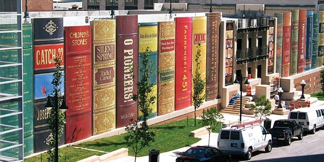 The exterior of a library wrapped with graphic film printed to look like giant books lined up.
