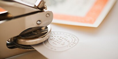 Embossed seal stamper imprinting a seal on the corner of a document.
