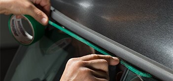A person applying 3M™ Perf Line Knifeless Tape to a car.
