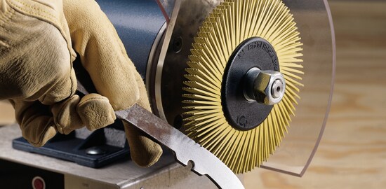 Un travailleur se prépare à utiliser une Brosse à soies radiales Scotch-BriteMC 3MMC pour polir une pièce de métal.
