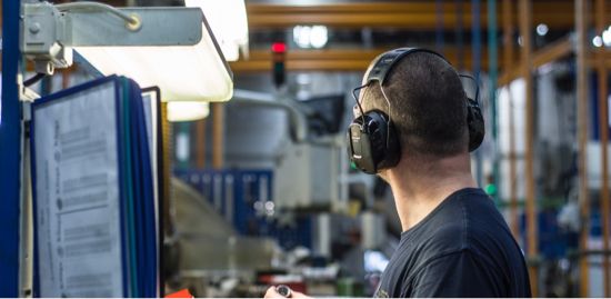 An engineer wearing hearing protection while looking through manuals.
