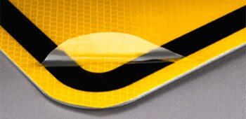 Une pellicule protectrice qui se fait peler d’un panneau de signalisation.
