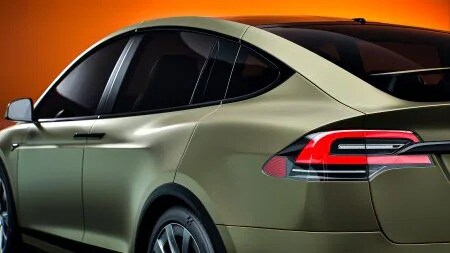 Rear passenger-side view of a red sports car with complex body lines, showcasing conformable automotive film.
