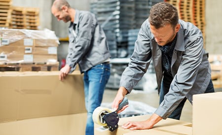 Ouvriers emballant des cartons dans un entrepôt.
