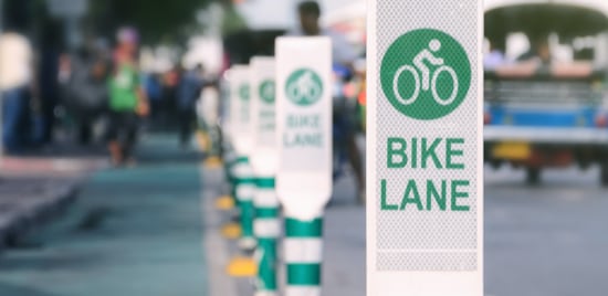 Une rangée de panneaux indiquant une bande cyclable protégée.
