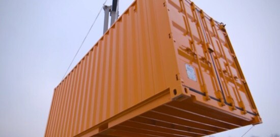 A video still of a shipping container suspended in the air.
