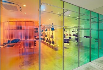 Vitrines de magasins ornées de finitions pour verre dichroïque 3M, dévoilant des nuances de vert, jaune, orange et rouge.
