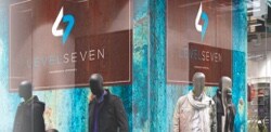 The window of a shop with mannequins and branded signage.
