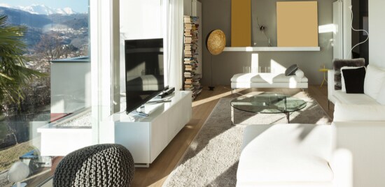 Un salon éclairé avec des fenêtres donnant sur une cour arrière.
