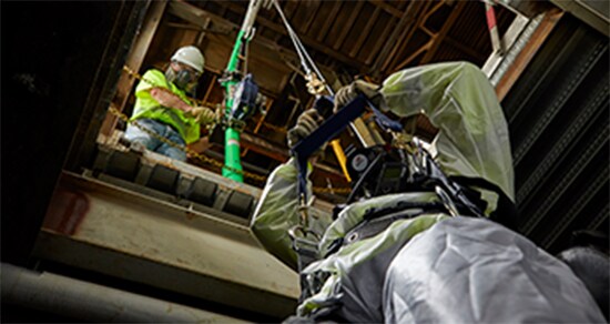 Looking up at worker entering confined space using a 3M™ Fall Protection system.
