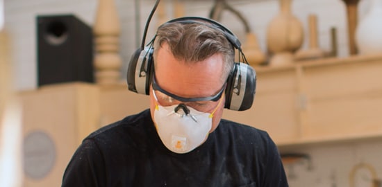 Un homme portant un dispositif de protection de l&rsquo;ouïe, un respirateur jetable et des lunettes de protection.