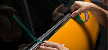 A person applying 3M™ Finish Line Knifeless Tape to a car door.
