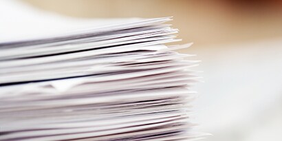 Une grande pile de papiers sur un bureau.
