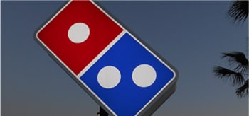 Enseigne lumineuse à l’extérieur d’un restaurant Domino’s Pizza.
