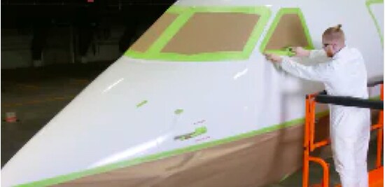 Person on a construction lift masking off the cockpit windows of a private jet.
