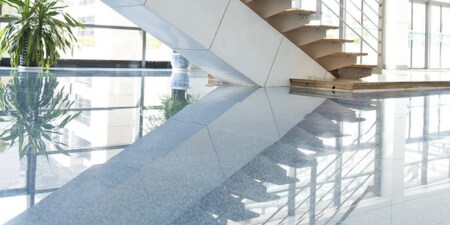 Entrée d’un bâtiment commercial avec un plancher en pierre hautement poli et réfléchissant.
