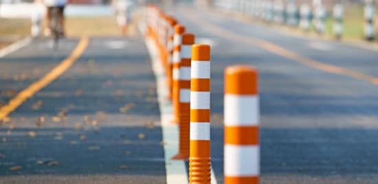 Line of orange bollards with white reflective tape to distinguish protected lane on road.
