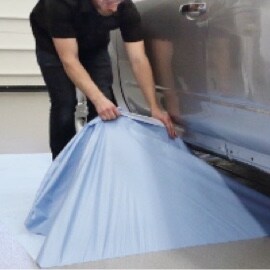 Un ouvrier retirant une pellicule de Tissu autoadhésif de protection contre les liquides 3M(MC) d’un plancher en béton sous un camion.