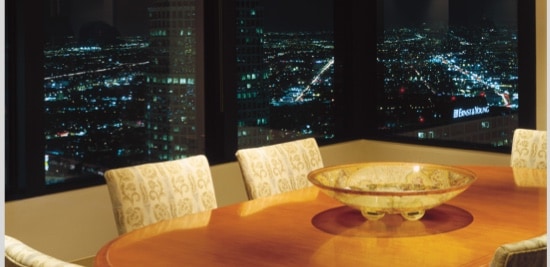 Une table de cuisine d’appartement donnant sur la ligne d'horizon de la ville de nuit.
