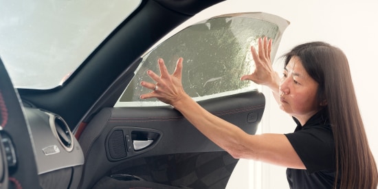 Auto technician installing window tint on the inside of a passenger car window.
