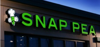 Enseigne de Snap Pea conçue avec une pellicule pour graphismes sur le côté d’un édifice la nuit.
