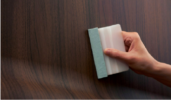 Une personne appliquant un film architectural à motif de bois.
