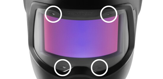 A welding helmet with a curved auto-darkening filter with four white circles around arc sensors in the filter window.
