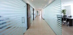 The hallway of an office with frosted horizontal stripes on glass windows.
