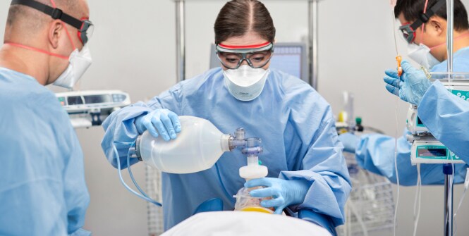 Des professionnels de la santé portant un équipement de protection s’occupent d’un patient en milieu clinique.
