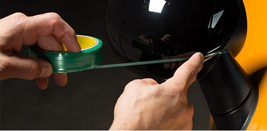 A person applying 3M™ Design Line Knifeless Tape to a car side mirror.
