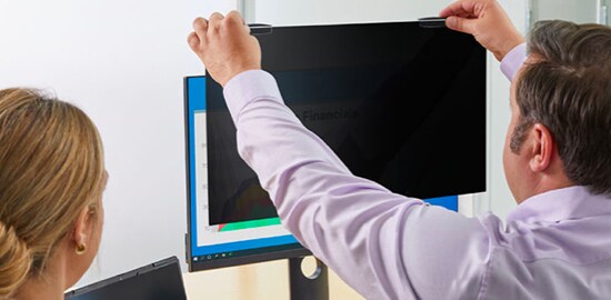 A man installing a 3M™ COMPLY™ privacy filter on his desktop monitor.
