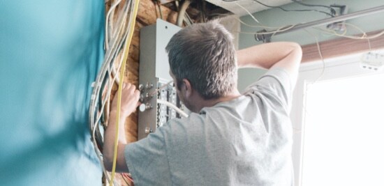Un électricien travaillant sur un boîtier de disjoncteurs.
